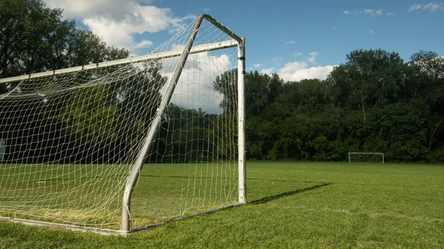 Terrain de foot synthétique vu du ciel avec joueurs, buts et city stade urbain